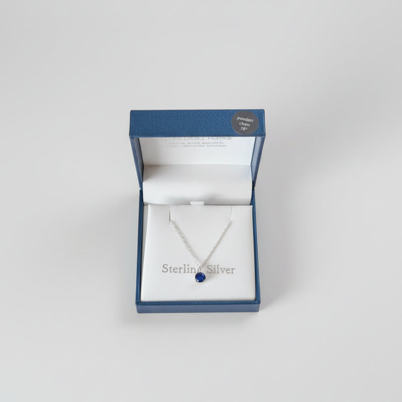 Sterling silver necklace in an open jewelry box on a textured gray surface